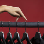 Illustratie van fast fashion: vrouw beweegt met haar vingers over een rek met kledinghangers.